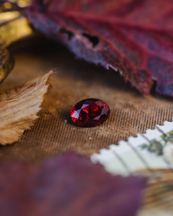 Pear brilliant cut Ant Hill garnet on a textured background with leaves