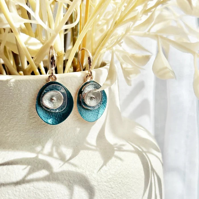 A pair of blue boho abstract flower earrings hand on the edge of a white vase with cream colored flowers. These earrings can be created in any color combination you like, making these the perfect gift to complete anyone's jewelry collection. These easy-breezy bohemian style layered disc dangle earrings are comfortable to wear and add a subtle pop of color. Wear them on their own, or go big and pair them with their matching abstract flower necklace.