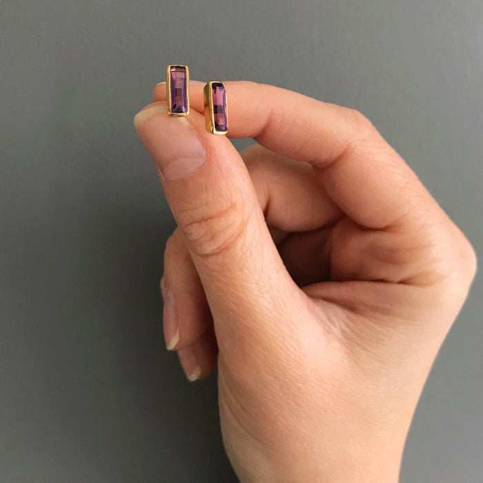 Hand holding tiny baguette birthstone stud earrings