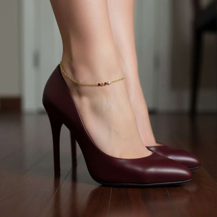 Model adjusting a dainty gold birthstone anklet, personalized ankle bracelet for moms, sisters, bridesmaids, or everyday wear.