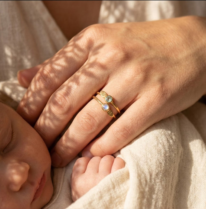 Custom family birthstone initial ring worn on hand with children’s birthstones, a meaningful mother’s ring or grandmother gift.