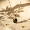 Natural Black Copper Obsidian oval necklace in yellow gold vermeil on beige fabric