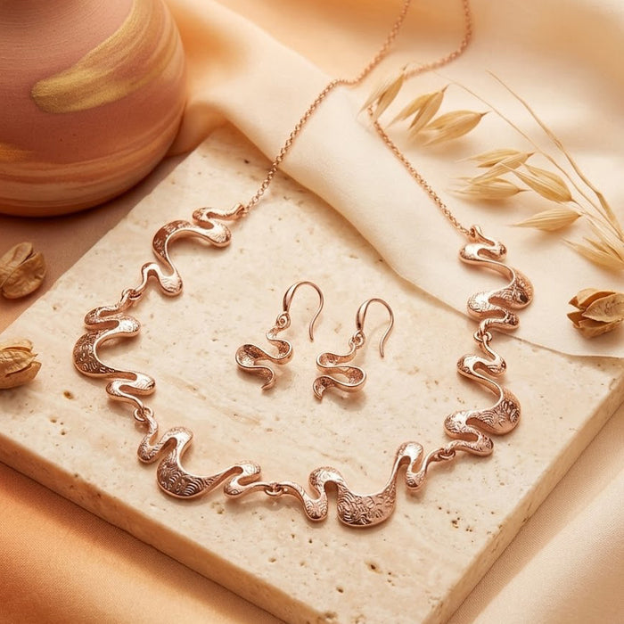Rose gold boho wave necklace and earrings set displayed on soft neutral fabric