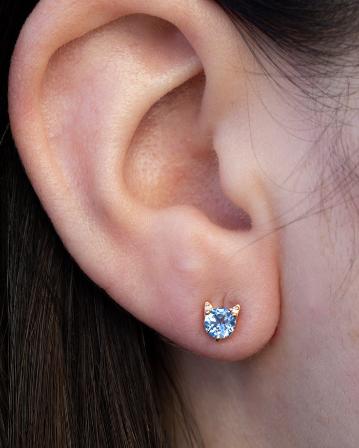 Montana sapphire cat earring on the ear against dark hair