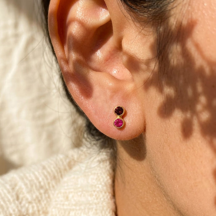 Dainty two-stone birthstone stud earrings worn on the ear, a delicate custom jewelry gift for mom, daughter, bridesmaid, sister, or best friend.