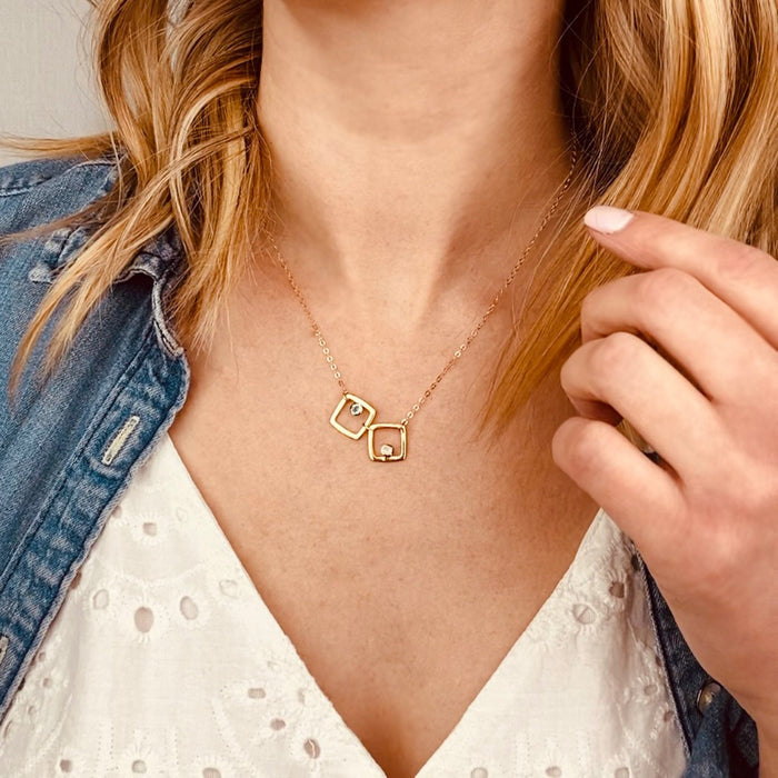 Model in white top is wearing the square open geometric necklace in gold filled with pink chalcedony and peridot birthstones.