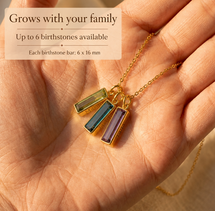 Personalized birthstone necklace for Mom with three engraved name bars shown on soft neutral fabric.