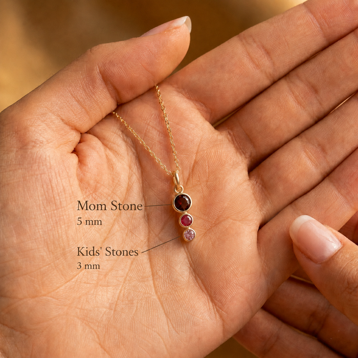 Hand holding a custom birthstone necklace with text showing a 5mm mom stone and 3mm kids’ stones, designed as personalized family jewelry.