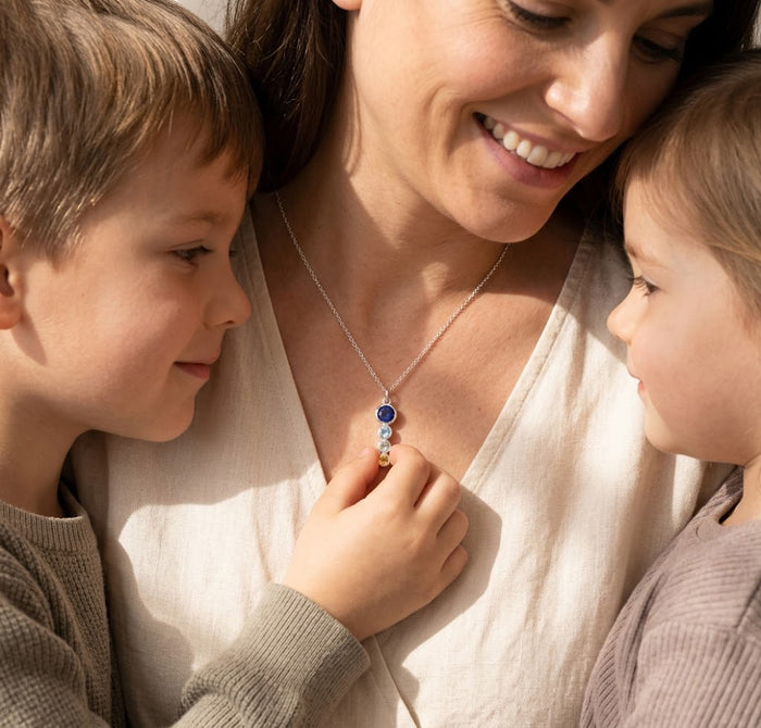 Mom wearing a custom birthstone necklace with her children, showing a sentimental family necklace made with birthstones for loved ones.