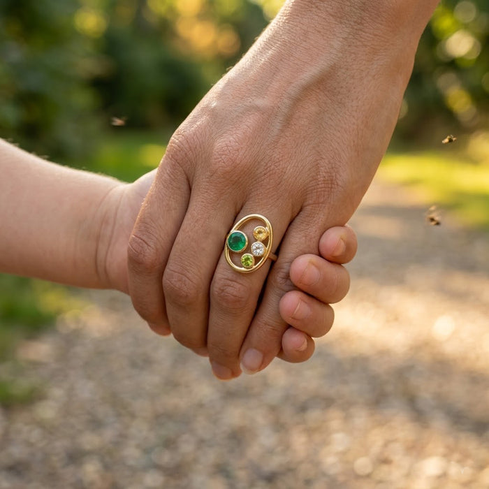 Mother and child holding hands while wearing a personalized birthstone ring with family gemstones.