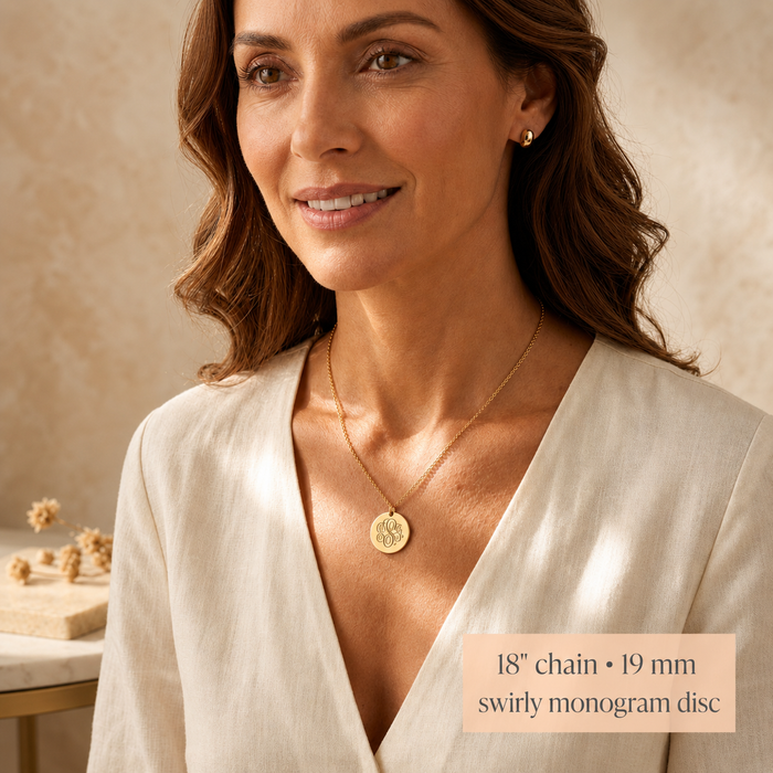 Model wearing a gold monogram necklace with an 18 inch chain and 19mm swirly monogram disc.