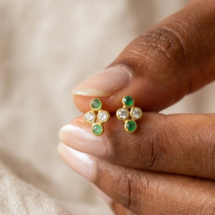 Tiny four birthstone cluster earrings held between fingers to show the petite scale and colorful natural gemstones