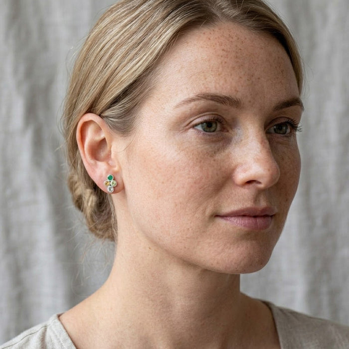 Blonde woman wearing petite personalized family birthstone earrings with four tiny bezel-set gemstones