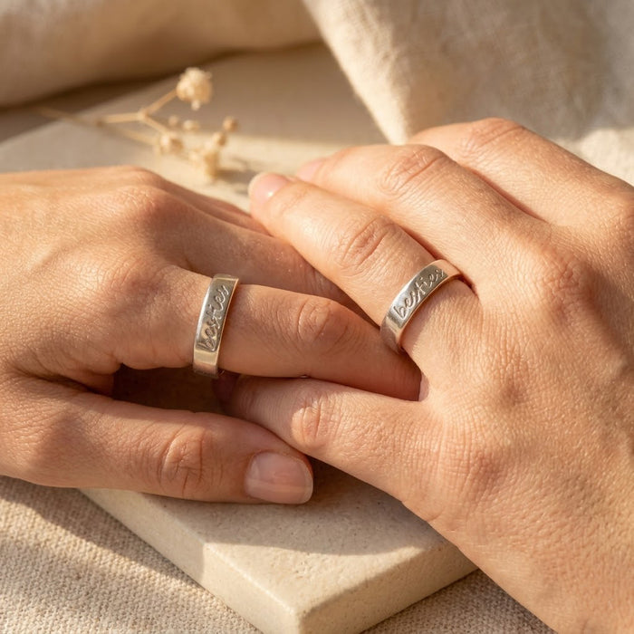 Model wearing slim personalized engraved band ring with custom handwriting on warm natural background.