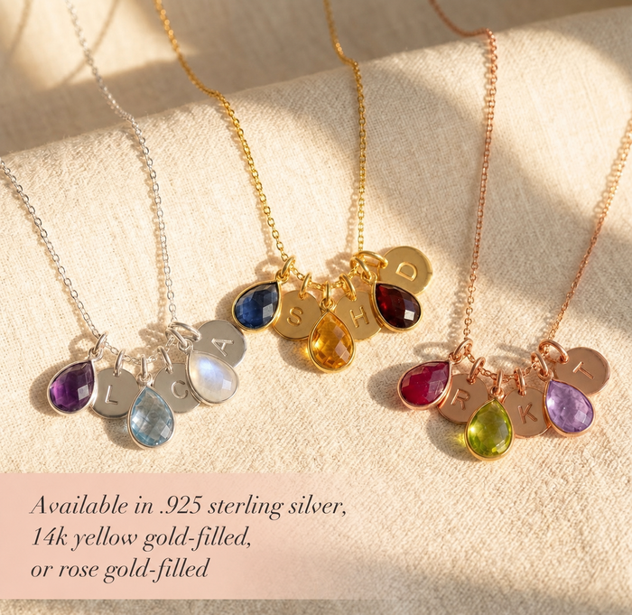 Gold, silver, and rose gold mom birthstone necklaces with colorful gemstone charms and initial discs on soft fabric.