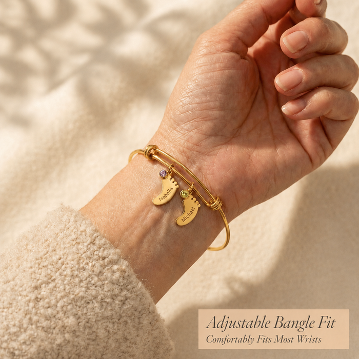 Woman wearing a gold personalized footprint bangle bracelet with engraved name charms, shown as a sentimental mom gift.