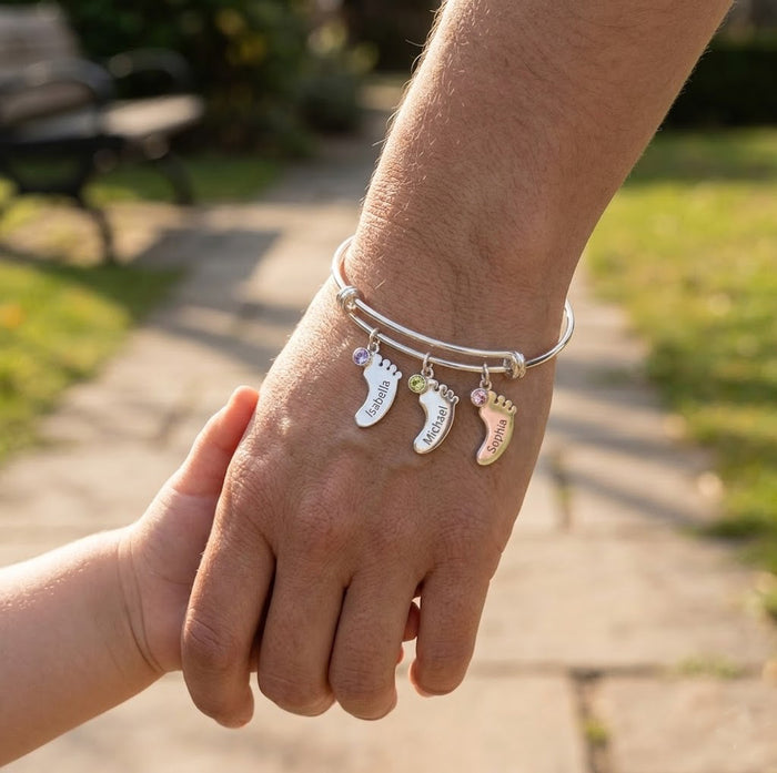 Silver custom footprint bangle bracelet worn outdoors, personalized with children’s names and birthstone charms.