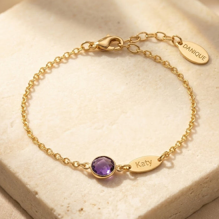 Custom birthstone name bracelet with one purple birthstone and engraved Katy name charm on gold chain.