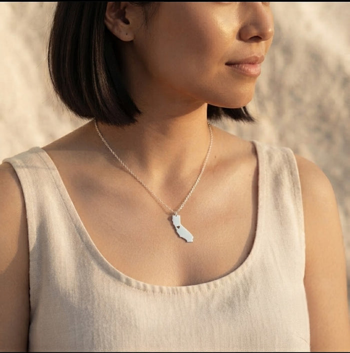 Woman wearing a personalized silver state or county map necklace