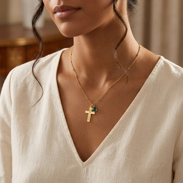 Woman wearing custom engraved cross and birthstone charm necklace, dainty personalized faith jewelry in gold