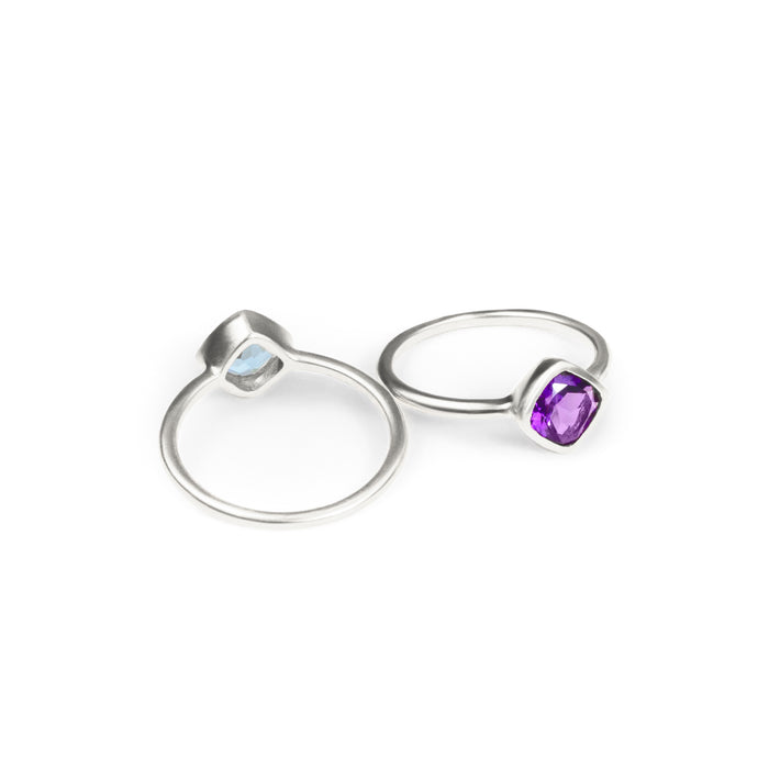 Back and front facing set of sterling silver diamond shape bezel set rings with purple amethyst birthstone.