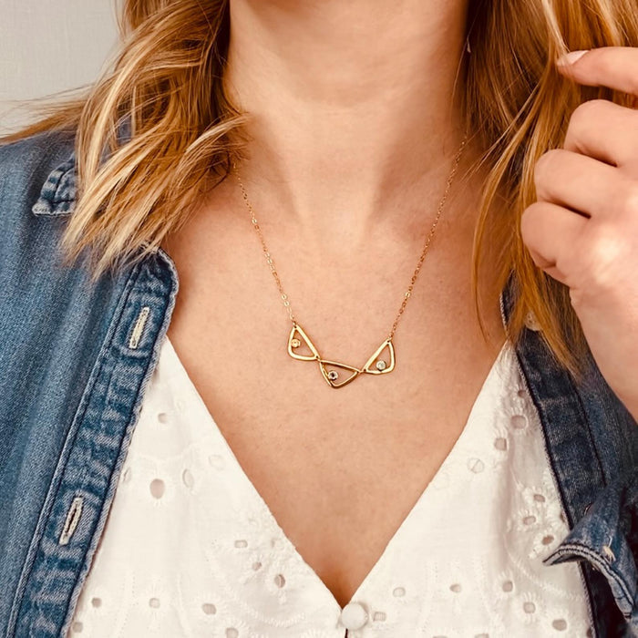 Model in white top is wearing a gold filled open triangle geometric necklace with citrine, purple amethyst and aqua chalcedony birthstones