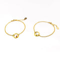 Two gold plated open circle pendant charm birthstone bracelets featuring  clear quartz and garnet birthstones. January birthstone, april birthstones. gemstone jewelry on white background.