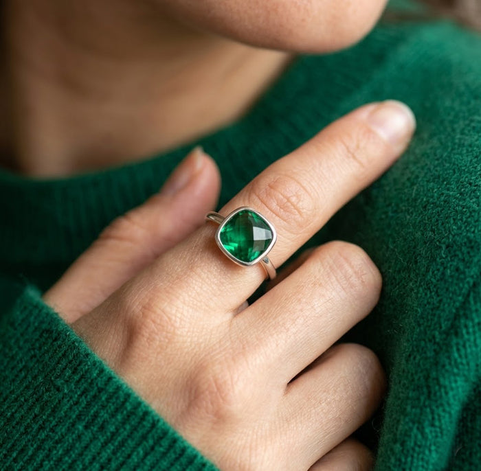 Model wearing an emerald quartz cushion ring with a green sweater, showing the bold green gemstone ring styled on hand.