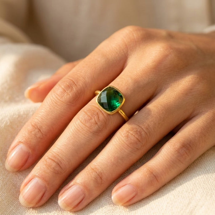 Emerald quartz cushion ring worn on hand, showing the green faceted cushion gemstone and slim gold band in natural light.