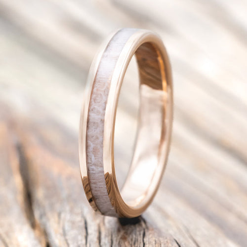Rose gold ring with wedding dress inlay on a wooden surface