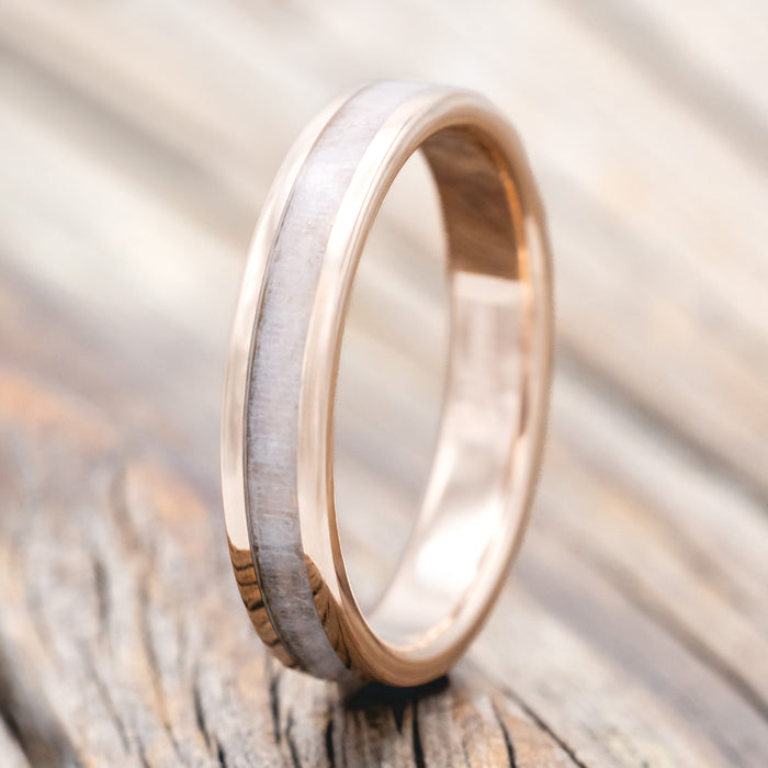 Rose gold ring with wedding dress inlay on a wooden surface