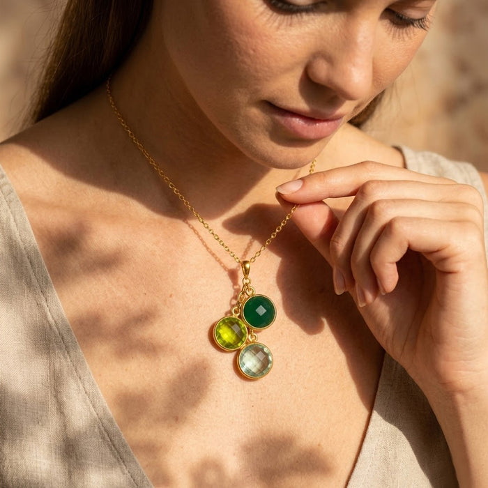 Model wearing green gemstone family birthstone necklace in yellow gold as a personalized mom gift