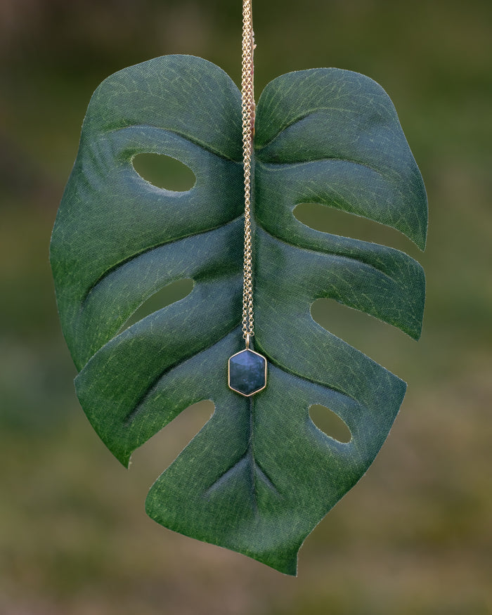 Necklace with moss agate pendant on a large green leaf against a blurred natural background