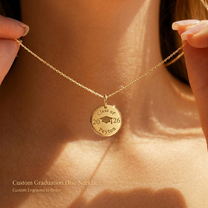 Gold personalized graduation disc necklace worn on model, engraved with Class of 2026, graduate name, and graduation cap design.