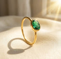 Green tourmaline oval ring shown in warm natural light with a delicate gold band.