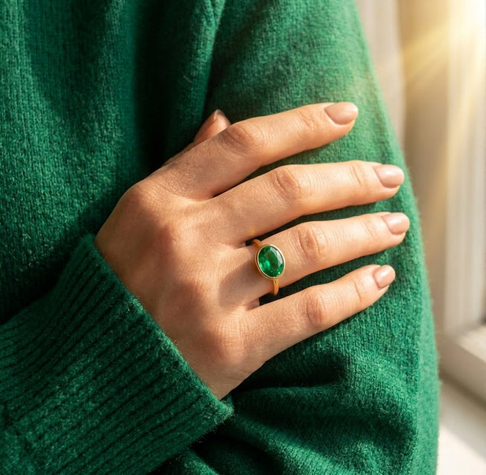 Dainty green tourmaline gemstone ring worn on a model’s hand with a green sweater.