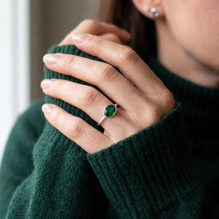 Model wearing a green tourmaline oval ring in a cozy sweater in soft natural light.