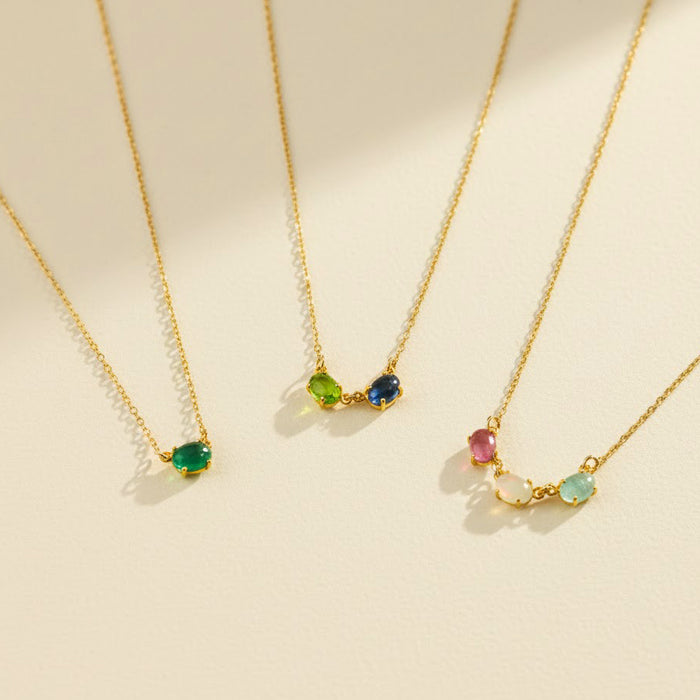 Horizontal oval birthstone necklace featuring custom multi-stone family jewelry design with dainty oval bezel gemstones, shown with emerald quartz, blue topaz, peridot, amethyst, and moonstone stones. Personalized mom necklace ideal for child name engraved gifts, Mother’s Day, birthdays, or Christmas gifting. Handmade in gold, rose gold, or sterling silver and perfect as a sentimental necklace for mom, grandma, or a new mother celebrating her children.