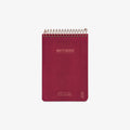Red notebook with spiral binding on a white background