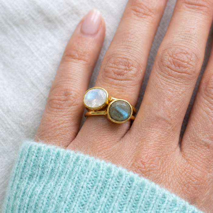 Faceted moonstone and labradorite gold ring set worn together on a hand with an aqua sweater.