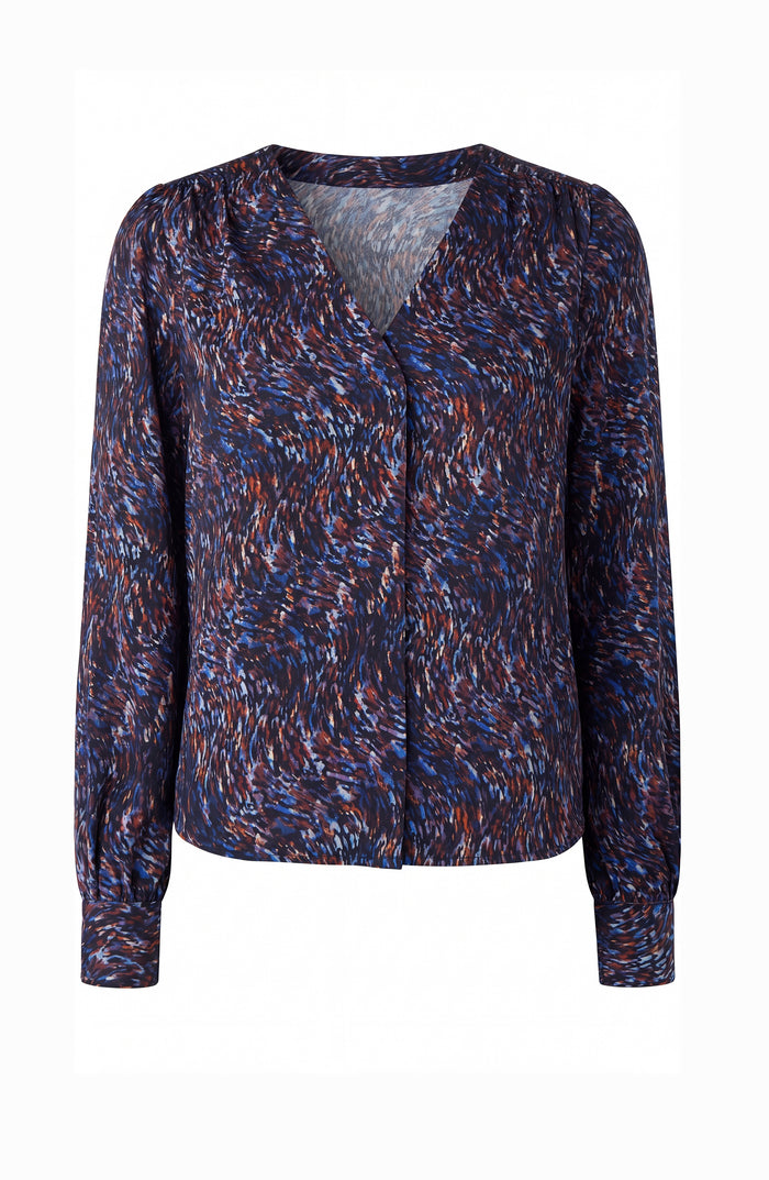 A women's long-sleeve blouse with a V-neckline, featuring an abstract, textured multicolor pattern in navy, blue, red, and white, displayed on a clean white background.