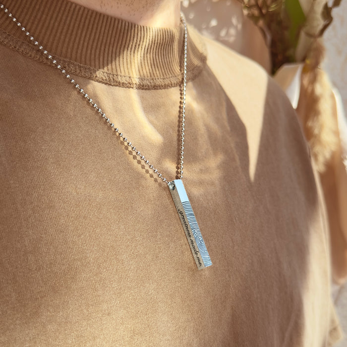 Men’s personalized stainless steel 3D bar necklace resting on soft sweater fabric, featuring custom engraving like fingerprint, GPS coordinates or anniversary date. Durable vertical bar pendant designed for everyday wear, perfect custom gift for boyfriend or husband celebrating milestones, birthdays or Father’s Day.