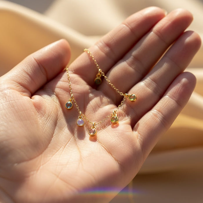 Close detail of birthstone charm necklace in hand — tiny custom gemstone’s birthstone necklace for mom gift