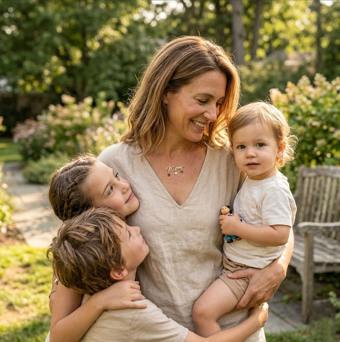 Mother holding her children while wearing a personalized Mom birthstone necklace as a meaningful family jewelry gift.