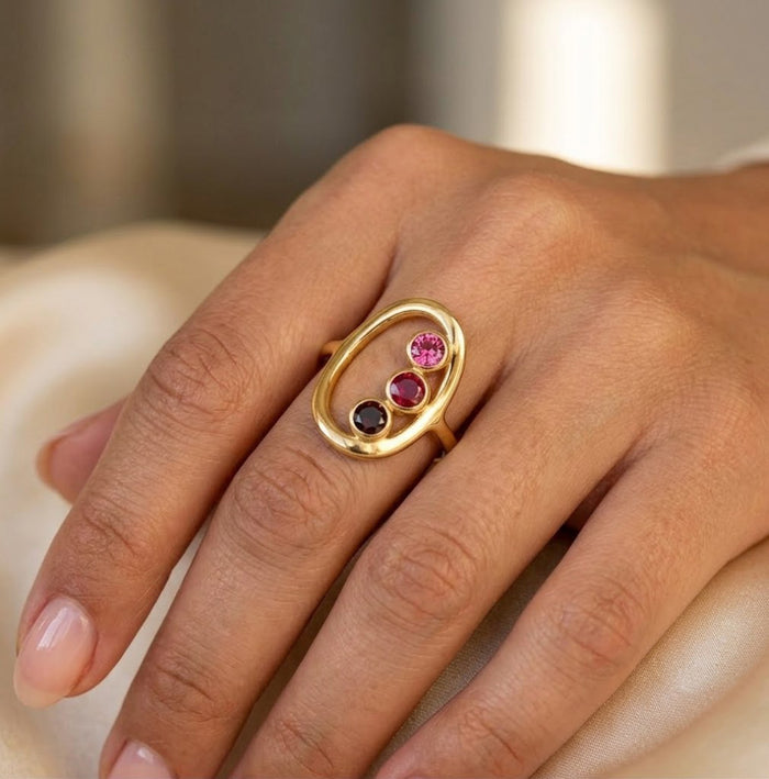 Close up of custom birthstone ring with three stones in gold setting