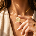 Personalized monogram disc necklace shown on model, featuring a round gold initial pendant on a delicate chain in warm natural light.