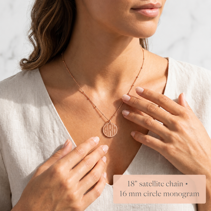 Model wearing a 16mm classic monogram disc necklace on a satellite chain, showing the pendant size and chain style.