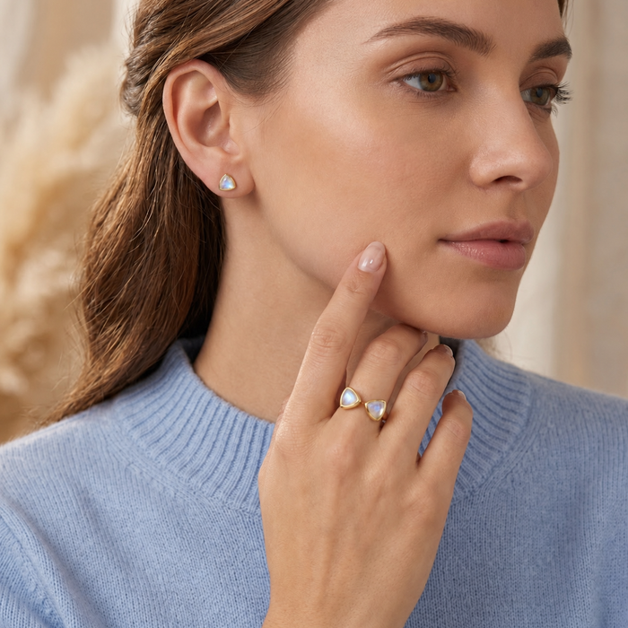 Model wearing moonstone triangle ring and matching stud earrings for a June birthstone jewelry set.