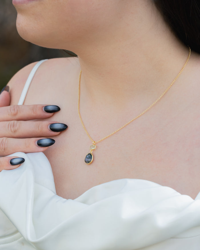 Gold necklace with moss agate & prasiolite pendant worn by a person in a white top