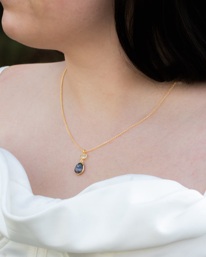 Gold necklace with moss agate & prasiolite pendant worn by a person in a white top